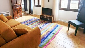 A living room with a sofa, TV stand, and a colorful rug. - Apartment Le Saint Jean 2 Confort et Cosy Résidence Les Rosalys (Villefranche de Conflent)