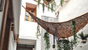 A narrow corridor with a wooden door, a black metal railing, and a woven ceiling with hanging plants. - Apartment Le Saint Jean 2 Confort et Cosy Résidence Les Rosalys (Villefranche de Conflent)