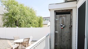 A wooden door with a metal handle, a white fence, and a patio with a table and chairs.