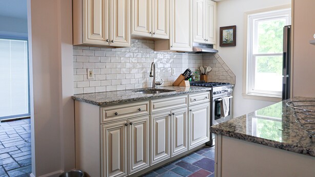 A kitchen with light-colored cabinets, a granite countertop, a stainless steel sink, and a built-in oven.