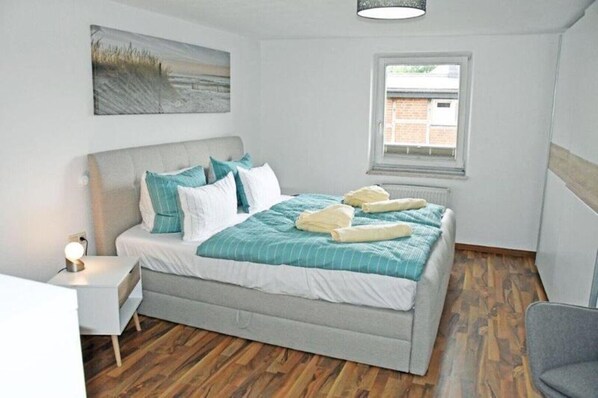 A bedroom with a bed, bedside table, and a window. - Vacation apartment 4a Lagoon (Sellin)