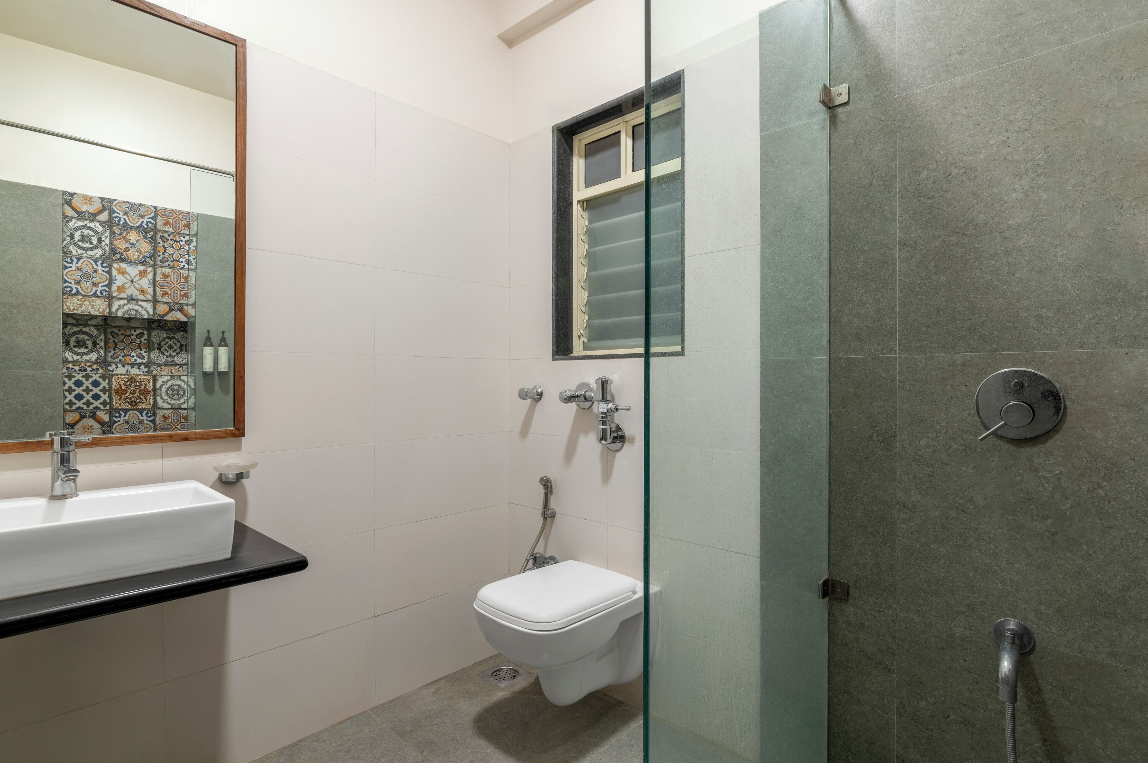 Un baño con un lavabo blanco, un inodoro y una zona de ducha con mampara de vidrio.