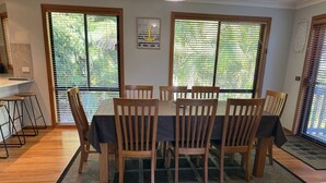 Een eetruimte met een ronde tafel, houten stoelen en een zwart tafelkleed.