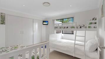 A bedroom with a bunk bed, a television, and a wardrobe.