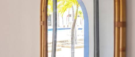 Espejo con marco de bambú que refleja una palmera y una estructura azul.