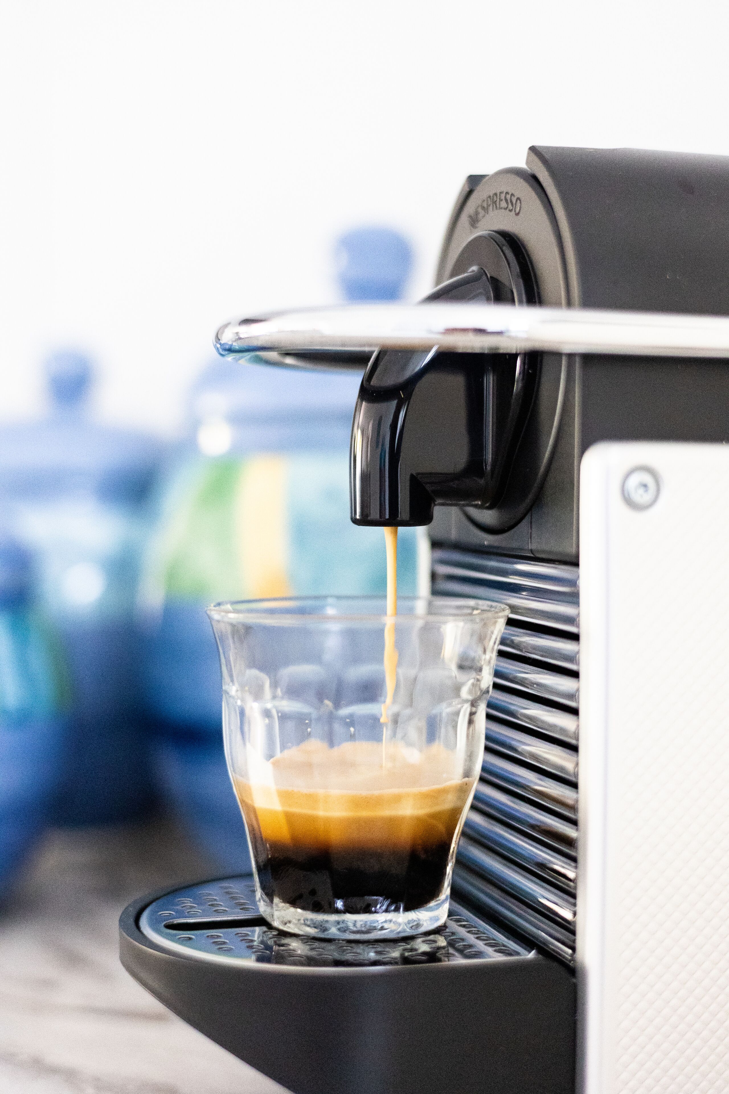 Une machine à café verse de l’espresso dans une tasse en verre transparent.