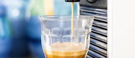 Une machine à café verse de l’espresso dans une tasse en verre transparent.