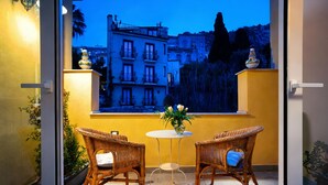 A balcony with wicker chairs, a small table, and a vase of flowers.