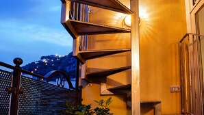 A spiral staircase with metal railings and a potted plant at the bottom.