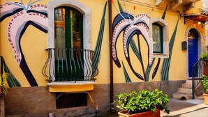 A building with a yellow facade, a balcony with a wrought iron railing, and a blue door.