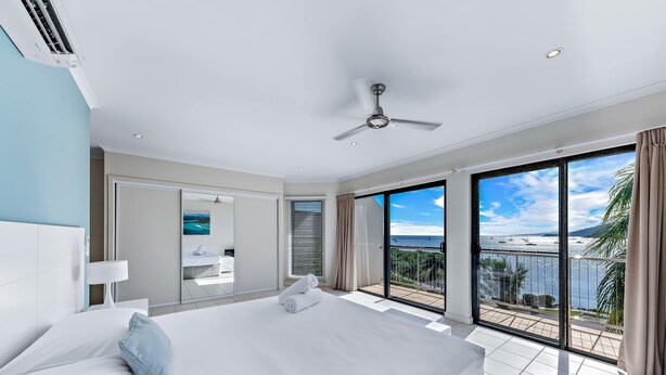 Ein modernes Hotelzimmer mit einem großen Bett, einem Deckenventilator und einem Balkon mit Meerblick.