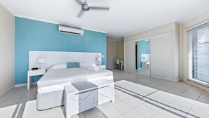 Ein modernes Schlafzimmer mit einem Bett, Nachttischen, einem Deckenventilator und einem großen Fenster.