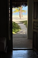 An interior doorway leading to a beach view with palm trees and a clear sky.