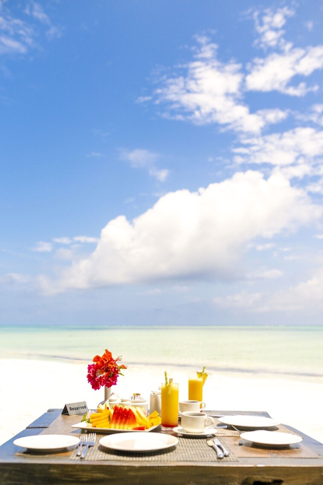 A table set for breakfast with a view of the ocean and sky.
