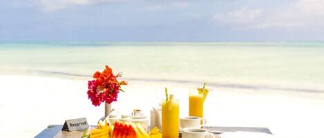 A table set for breakfast with a view of the ocean and sky.