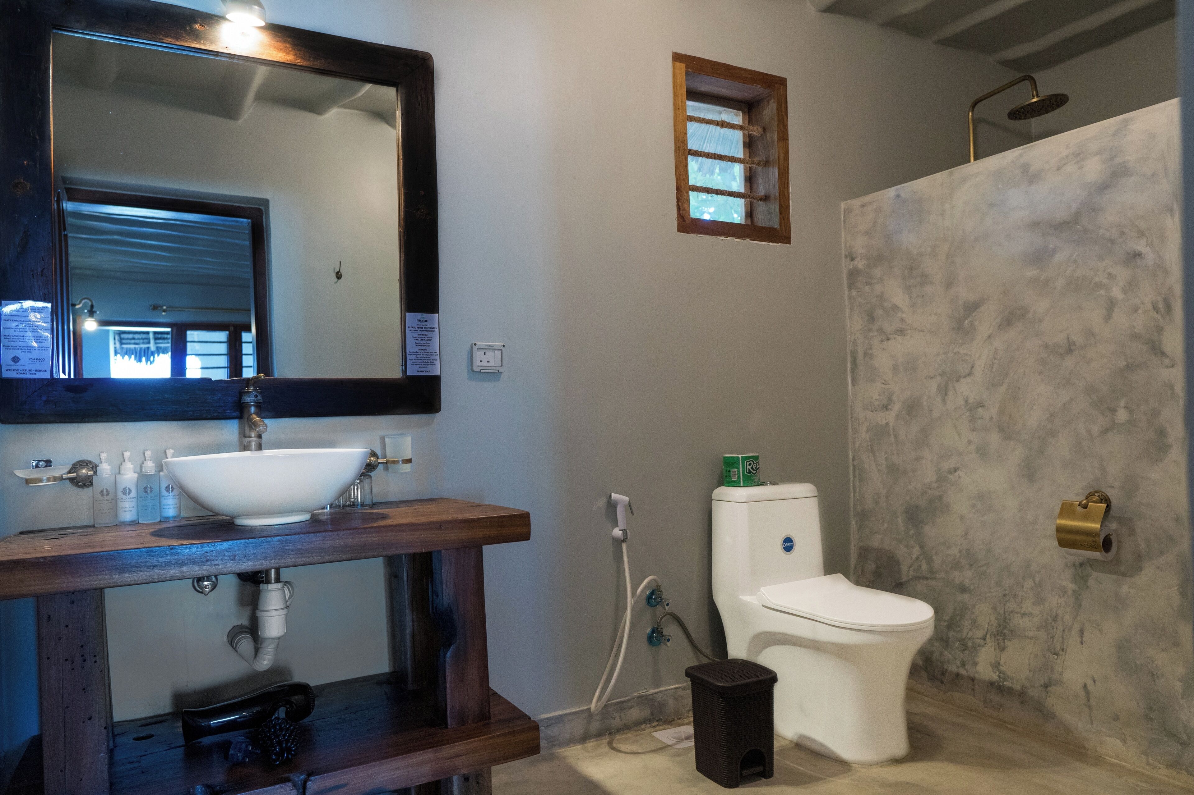 A bathroom with a wooden vanity, a white sink, a mirror, a toilet, and a shower area.