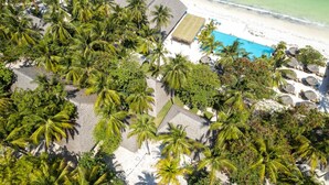An aerial view of a resort with multiple thatched-roof structures, a pool, and a beach. - Ndame Paje Hotel (Paje)