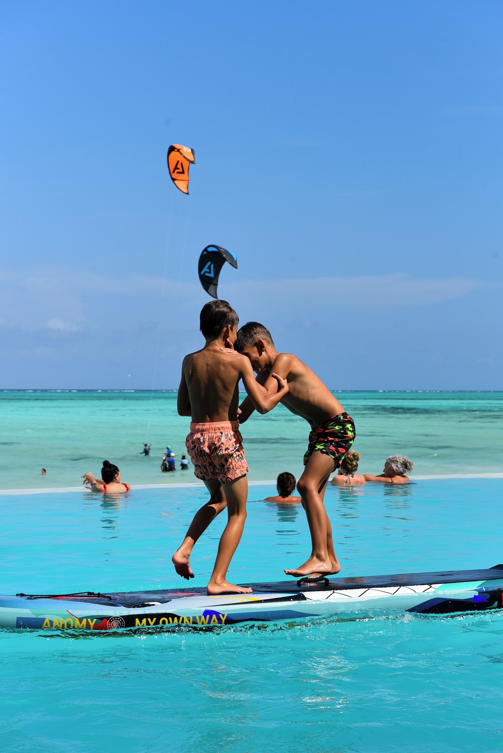 A beach scene with people on a paddleboard.