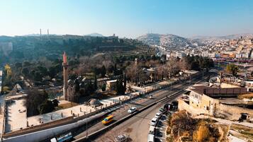 A cityscape with a prominent historical building featuring a tall minaret and domed structures, adjacent to a modern road with vehicles.