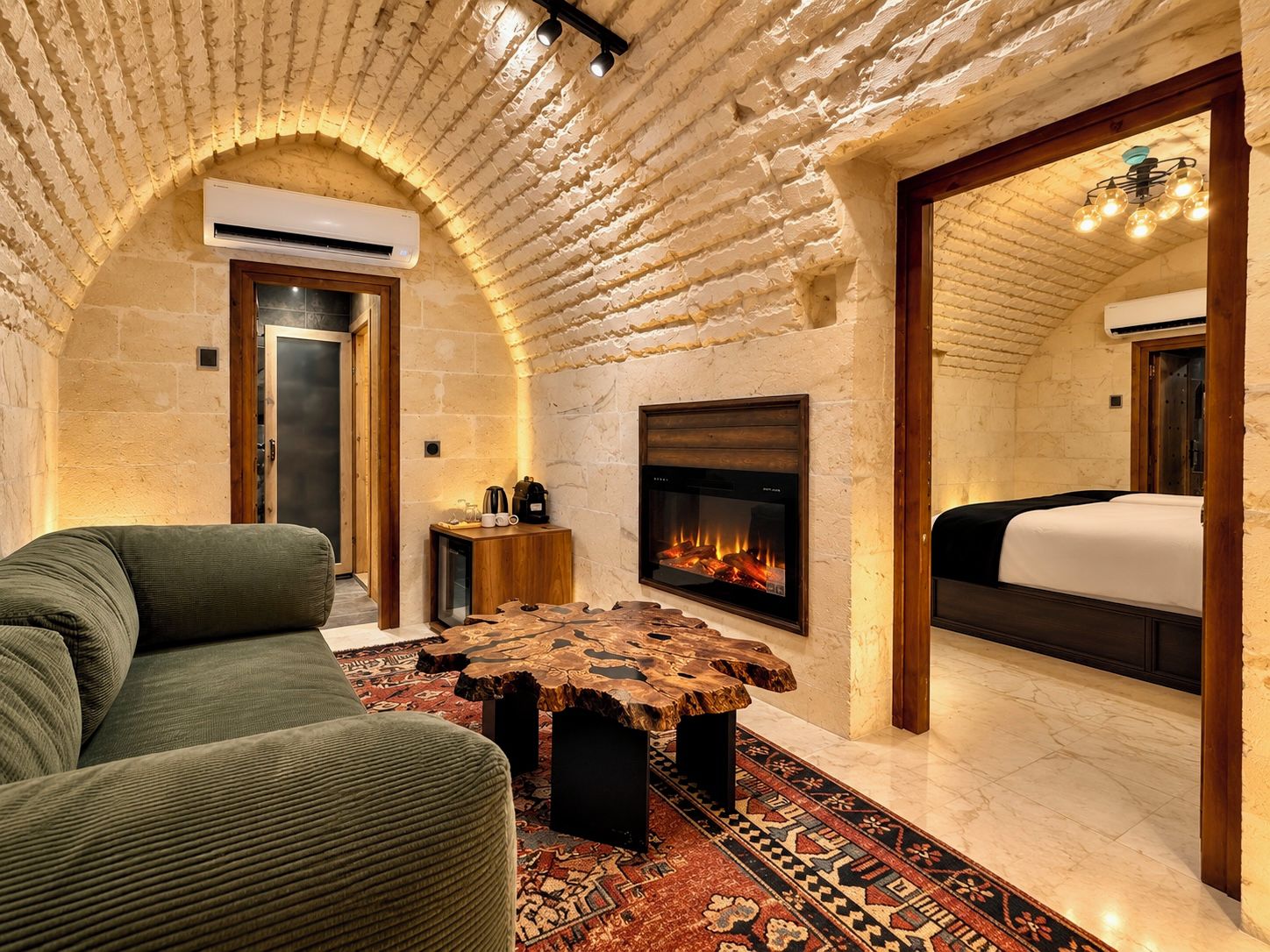 Una habitación acogedora con chimenea, un sofá, una mesa de centro y una cama.