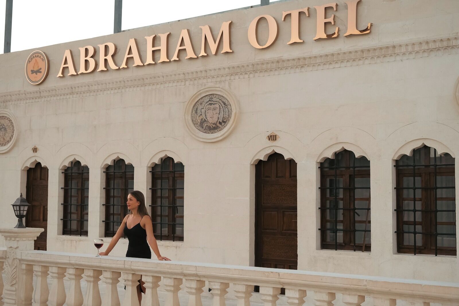 The exterior of the Abraham Hotel with a signboard, arched windows, and a balcony railing.