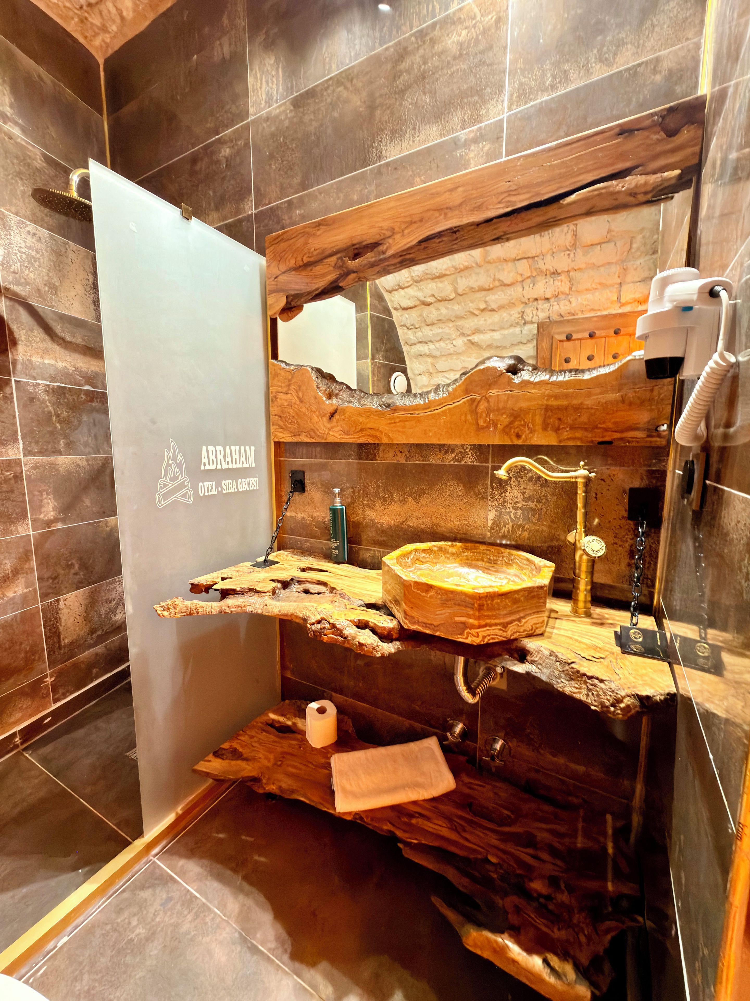Un baño con un diseño único de lavabo de madera, un espejo y un dispensador de toallas.