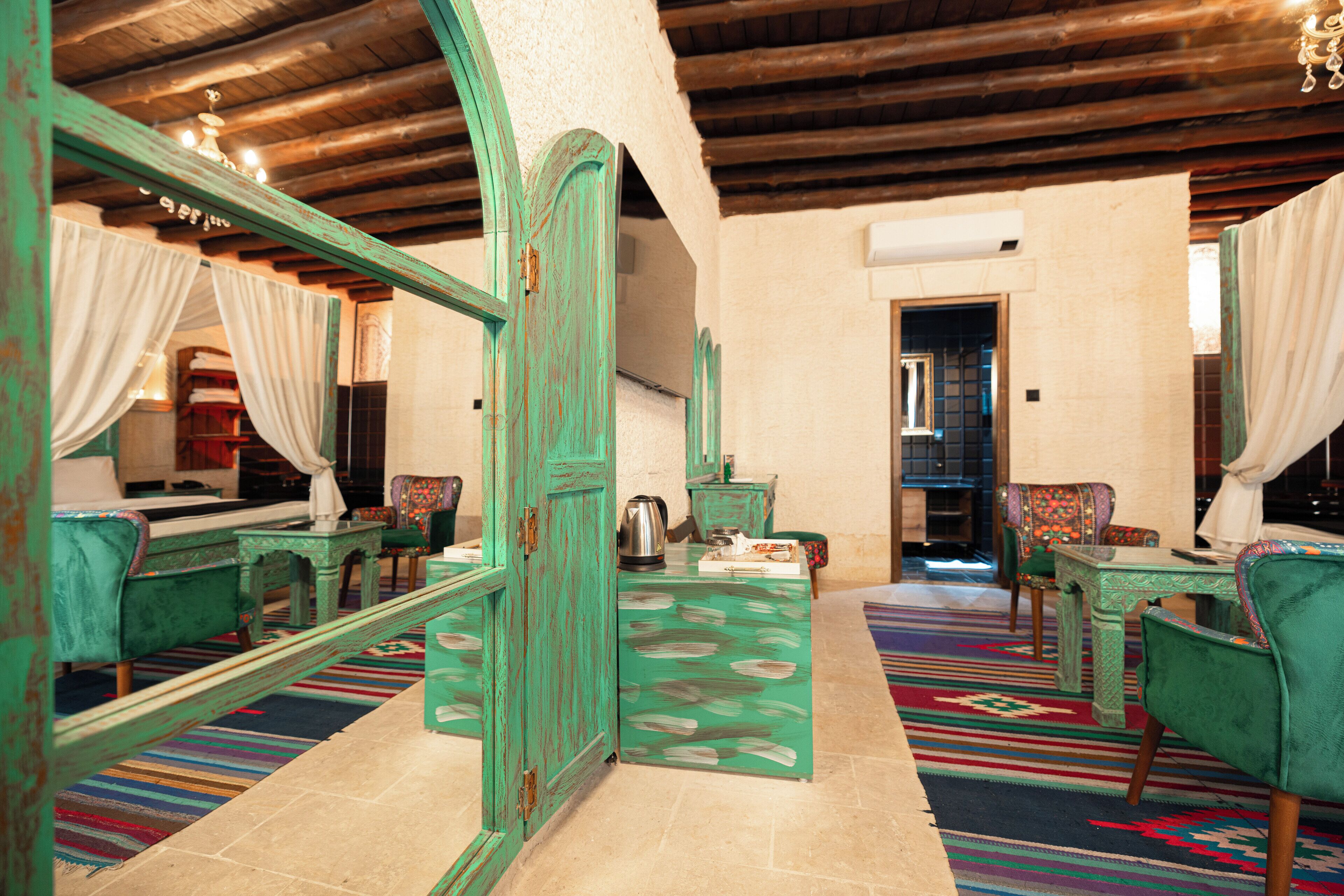 Una stanza con soffitto in legno, arredi verdi e un tappeto colorato.