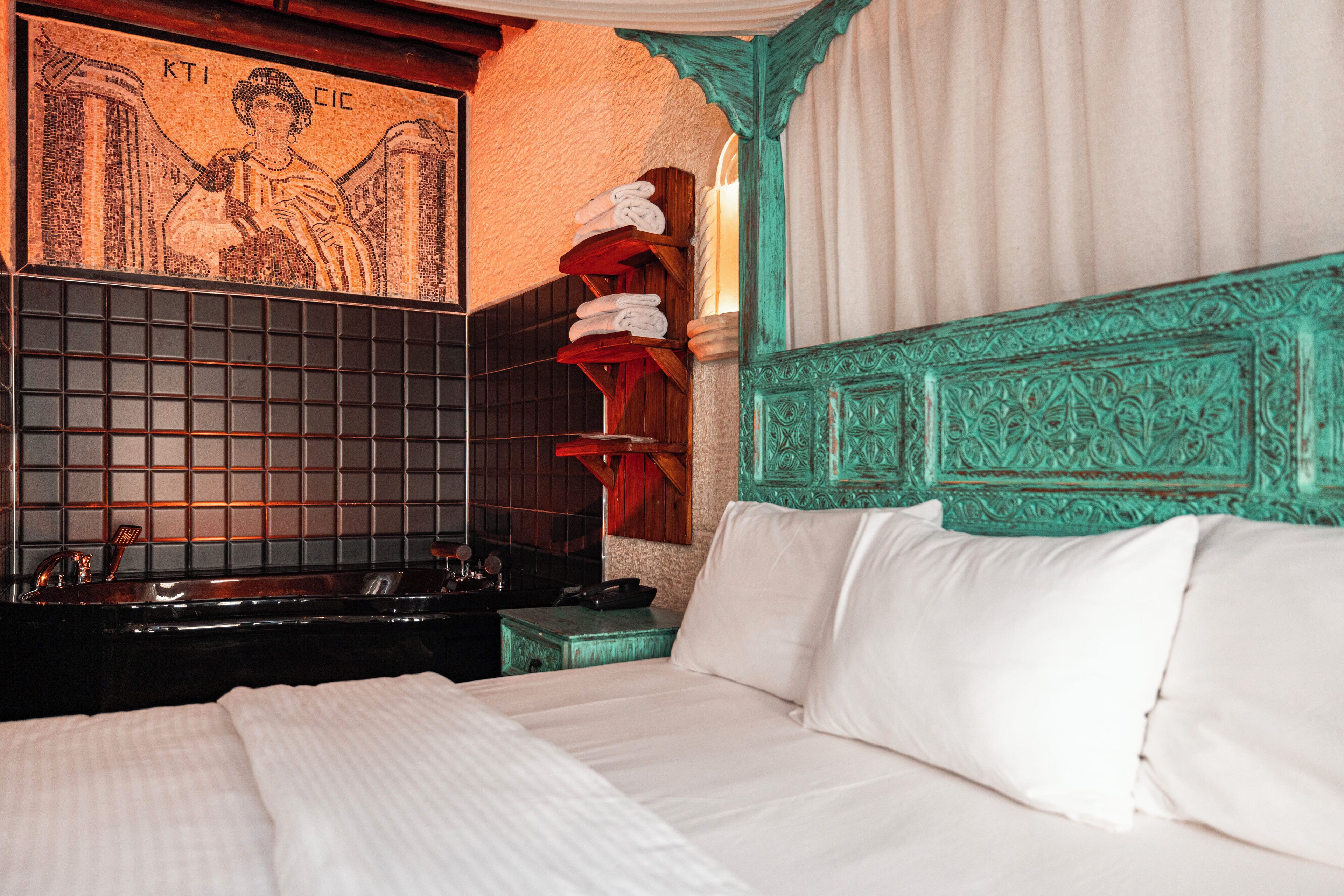A hotel room with a large bed, a wall-mounted sink, and a decorative wall piece.