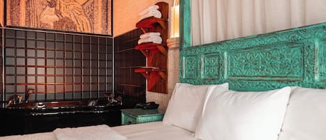 A hotel room with a large bed, a wall-mounted sink, and a decorative wall piece.