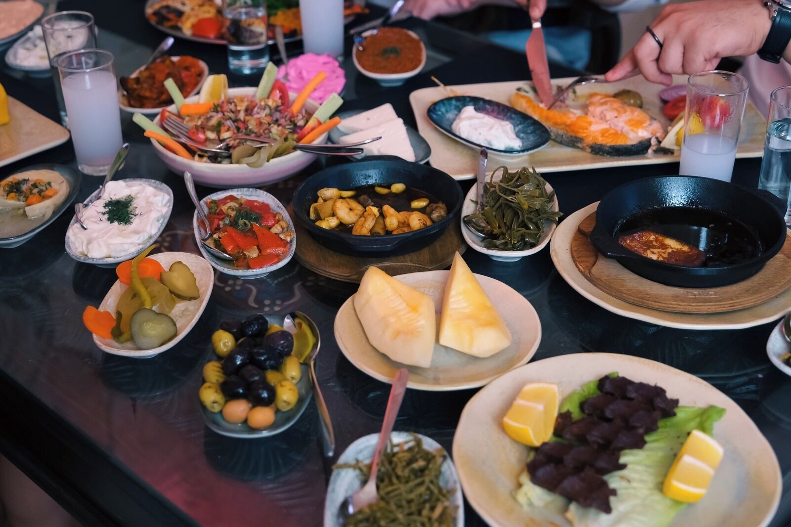 Una mesa con varios platos, entre ellos ensaladas, carnes y quesos.