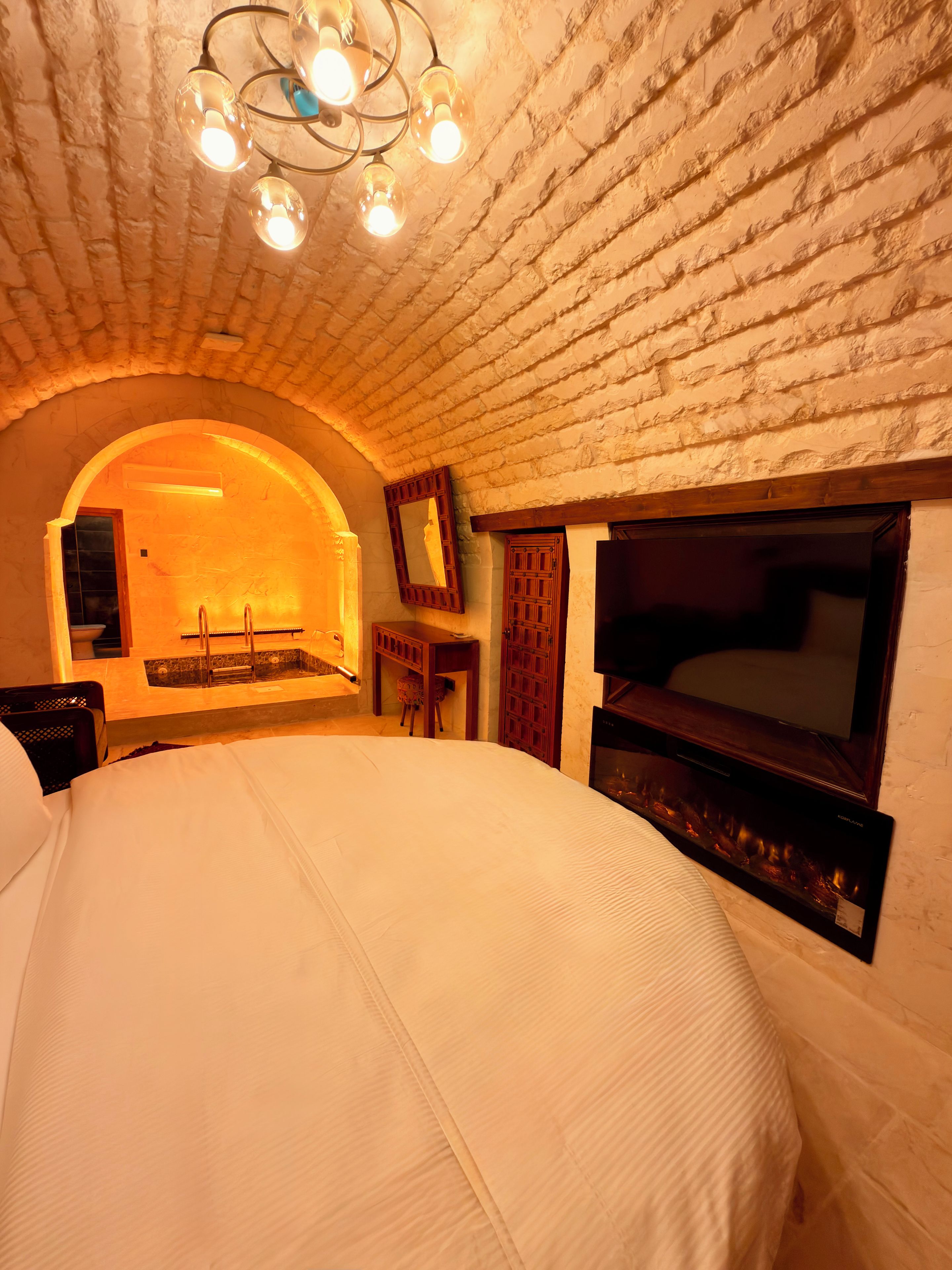 Un dormitorio con una cama grande, televisión y chimenea.