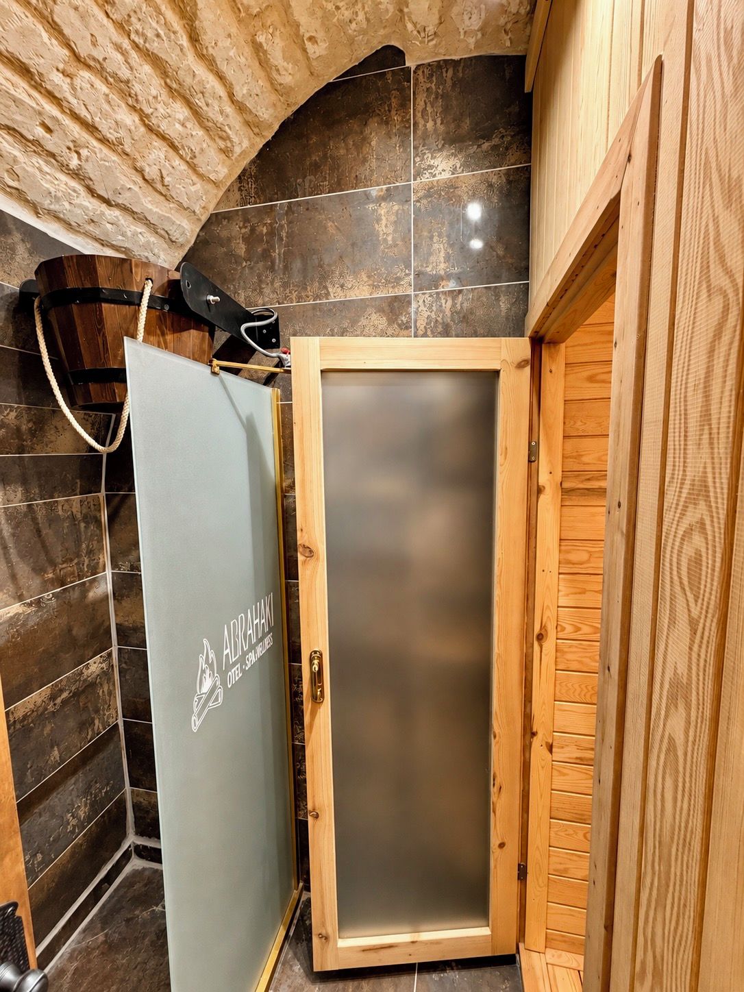 Un baño con puerta de madera, perchero y zona de ducha.