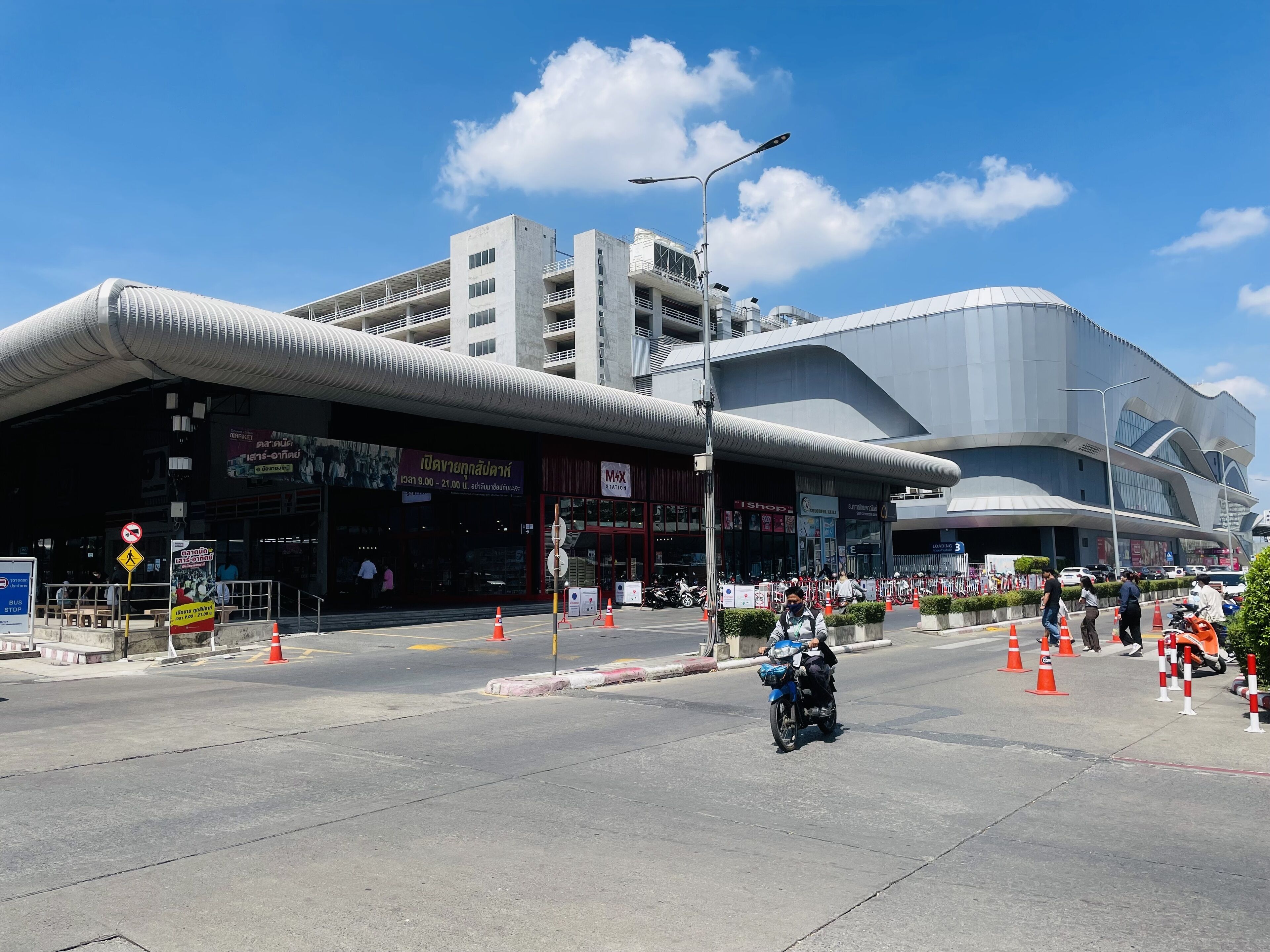 Un edifici modern amb façana corbada, una estació MAX i una parada d'autobusos.