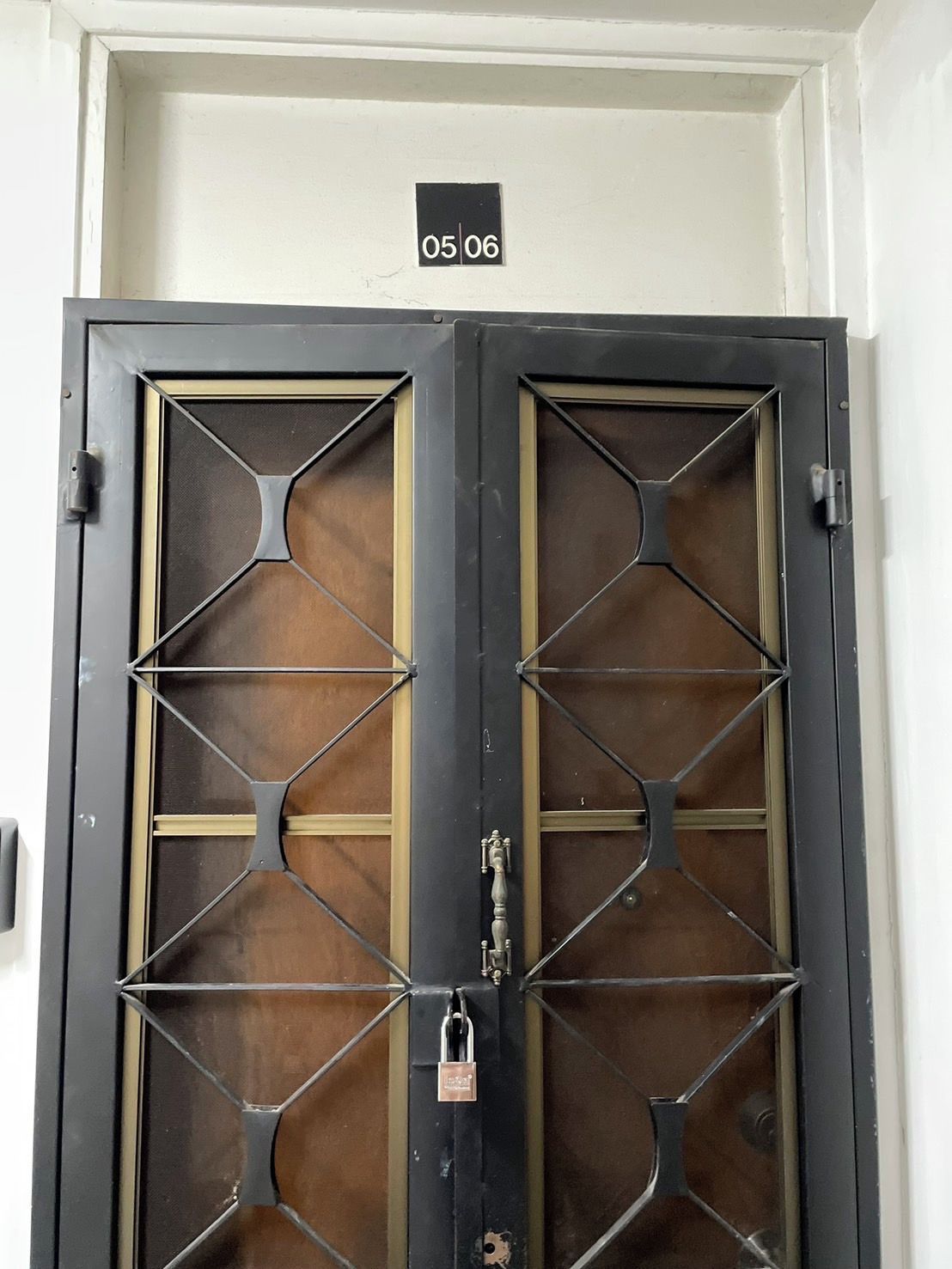 A double door with a lock and a sign above it.