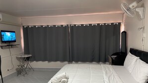 A hotel room with a bed, a TV, a small table, and a chair. - Muangthong C3, C4 near Impact by Anna (Pak Kret)