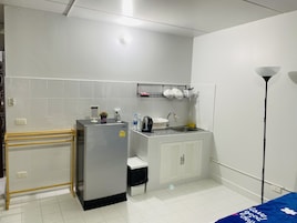 Uma cozinha compacta com geladeira, pia e bancada pequena.