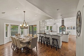 A spacious kitchen with a central island, dining area with chairs, and a chandelier. - Pebble Beach's Los Altos (Pebble Beach)