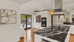 A modern kitchen with white cabinetry, a black marble island, and recessed ceiling lights. - Pebble Beach's Los Altos (Pebble Beach)