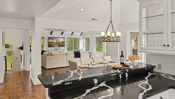 A modern kitchen with a marble island, white cabinetry, and a dining area with a sofa and table. - Pebble Beach's Los Altos (Pebble Beach)