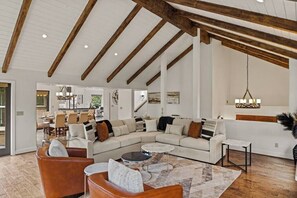 A spacious living room with a large sectional sofa, a coffee table, and a dining area in the background. - Pebble Beach's Los Altos (Pebble Beach)
