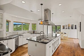 A modern kitchen with white cabinetry, a central island, and a large window. - Pebble Beach's Los Altos (Pebble Beach)
