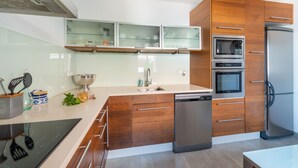 Une cuisine moderne avec des meubles en bois, un four encastré, un lave-vaisselle et un réfrigérateur en acier inoxydable.