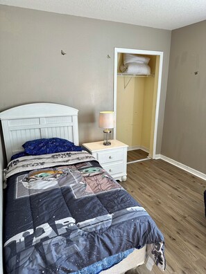 Ein Schlafzimmer mit Bett, Nachttisch, Lampe und Schrank.