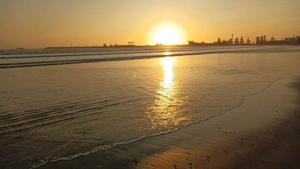 A beach at sunset with the sun reflecting on the wet sand. - Riad El Baze (Essaouira)