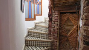 A staircase with checkered tiles leading to a door with a geometric pattern. - Riad El Baze (Essaouira)