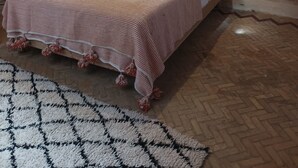 A bedroom with a brick fireplace, a bed with white bedding, a wooden headboard, and decorative plates on the wall. - Riad El Baze (Essaouira)