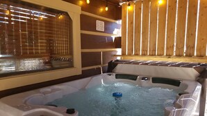 Ein Whirlpool mit Holzterrasse und einem Fenster mit Jalousien.