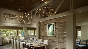 A dining area with a long table, chairs, and a patterned carpet. There are hanging light fixtures and a large framed picture on the wall. - AMELIA ISLAND PLANTATION VILLA 2/2 IN A GATED COMMUNITY JUST OFF BEACH LOCATION (Fernandina Beach)
