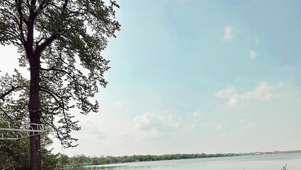 A wooden deck with benches, overlooking a calm lake with docks. - The Darling Cabin, 60's Charm + Modern Flair (Alexandria)