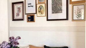 A room with a wooden bench, a vase with flowers, and a wall with framed artwork. - The Darling Cabin, 60's Charm + Modern Flair (Alexandria)